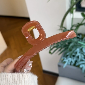 Close-up of caramel brown hair claw clip with glossy finish and durable golden spring