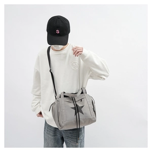 Detail showing grey travel bag with black star logo and adjustable shoulder strap