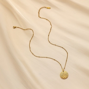 Macro shot of gold zodiac coin pendant featuring Virgo on a beaded chain necklace