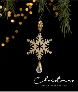 Close-up of a golden Christmas snowflake pendant with crystal beads on a pine branch