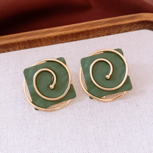 Close-up of vintage square earrings in retro green lacquer with golden spiral lines