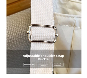 Detail of silver metal adjustment buckle and woven strap on a white quilted shoulder bag