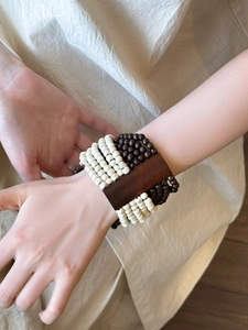 Detailed view of bohemian multilayer wood bead bracelet on wrist with dark wood plaque