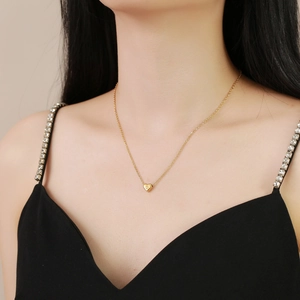 Elegant gold heart pendant necklace with engraved letter worn on model for jewelry display