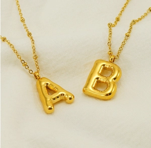 Detailed macro view of 18K gold plated puffy balloon A and B letter pendants on satellite chain