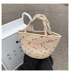 Detail of hand-woven straw bucket bag with colorful polka dots and thick rope handles