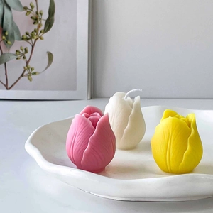Three tulip shaped scented candles in pink white and yellow on a minimalist tray