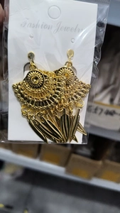 Close-up of golden bohemian tassel earrings with sun pattern in clear plastic packaging