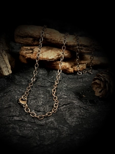Detailed macro view of vintage bronze link chain necklace on rustic wood and fabric