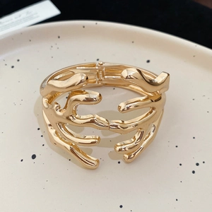 Close-up of golden coral branch cuff bracelet with polished finish in ceramic tray