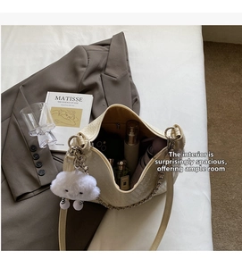 Detail of cream woven tote bag showing large capacity for essentials and plush charm