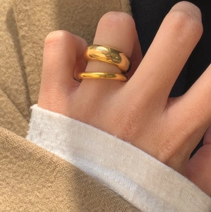 Close-up of dual stackable gold finish rings worn over a warm wool coat sleeve