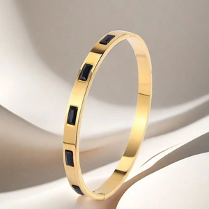 Detail of gold-plated stainless steel hinge bangle with black enamel insets