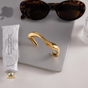 Bracelet manchette doré minimaliste sur un bureau moderne avec des accessoires élégants