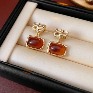 Vue macro de boucles d'oreilles carrées plaquées or avec résine ambre en boîte cadeau
