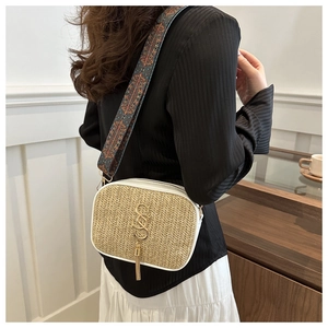 Detail of woven straw bag featuring white leather trim and colorful ethnic style strap