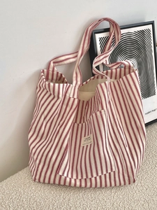 Large red and white striped canvas tote bag in a minimalist interior home setting