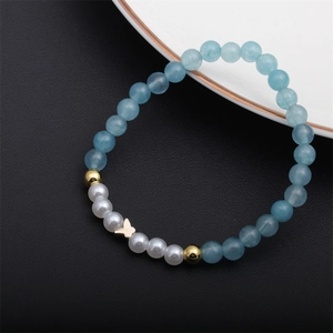 Bracelet en perles bleues avec perles blanches et breloque papillon doré élégant