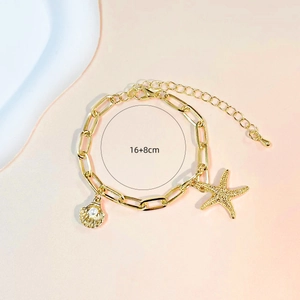 Gold chain bracelet with starfish and shell pearl charms on soft pink background