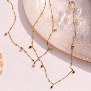 Detail of 18K gold-plated layered necklace with green and white zircons on water-drop surface
