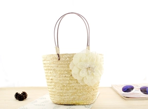 Detalle del bolso de paja con una gran flor de tela 3D y una perla en el centro