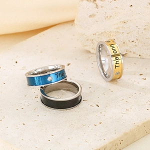 Detail of titanium steel rings in blue black and gold with engraving and single zircon