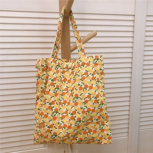 Vue détaillée du mini sac cabas en toile à fleurs avec motifs d'orange et bouton pression
