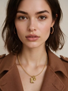 Close-up of golden boot pendant necklace and textured hoop earrings on a fashion model