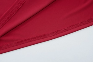 Macro shot of dark red fabric texture and overlock stitch detailing on dress hemline