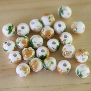 Macro shot of white ceramic beads with yellow floral patterns on light wood background