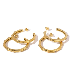 Gold C-shaped hoop earrings with white and colorful zircon crystals on white background