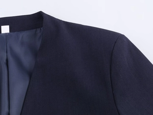Detailed close-up of dark blue blazer shoulder seams and smooth plain weave fabric