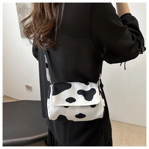 Fashionable cow print crossbody bag worn by a model in a minimalist indoor setting