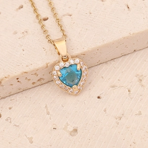 Macro shot of gold heart necklace with a blue gemstone center and clear zircon border