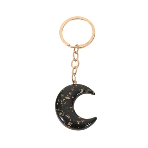 Detail of crescent moon keychain with black resin and gold glitter finish