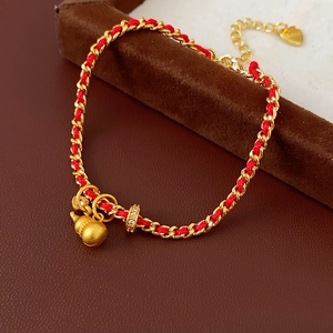 Vue détaillée du pendentif gourde plaqué or et du bracelet tressé rouge élégant