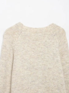 Detailed view of the ribbed crew neck and soft wool blend texture on a beige knit sweater