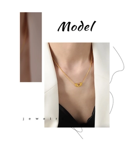 Détail du collier chaîne serpent dorée avec pendentif géométrique en U porté par le modèle