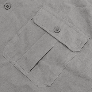 Detail of grey linen shirt showing front pocket flap and matching round resin buttons