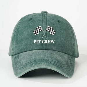 Close-up of PIT CREW embroidery and checkered flags on a washed green cotton baseball cap