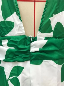 Detail of green leaf print dress featuring V-neck seam and hidden back zipper