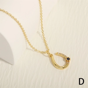 Detailed macro view of gold U-shaped pendant necklace with blue and white zircon stones