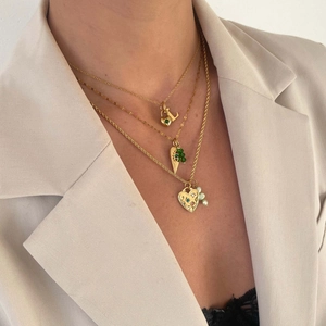 Detail of layered gold necklace set with green emerald charms and pearl heart pendant