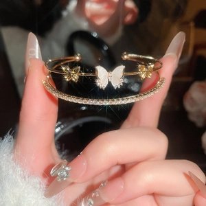 Detailed macro view of a layered gold butterfly bracelet with zircon inlay and mother-of-pearl