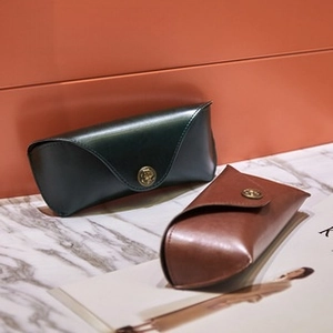 Detail view of vintage leather eyewear cases in green and brown with embossed metal snap