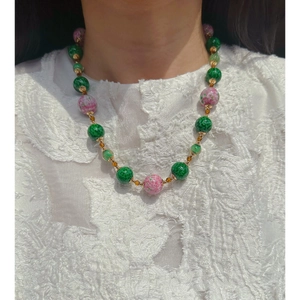 Handmade beaded necklace with green and pink glass beads and gold spacers on a model