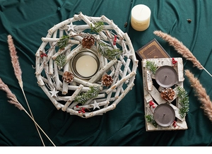 Detail of Nordic wooden candle holder with pine cones and red berries on green fabric