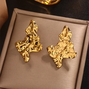 Detailed macro view of 18K gold-plated earrings with irregular lava texture in a jewelry box