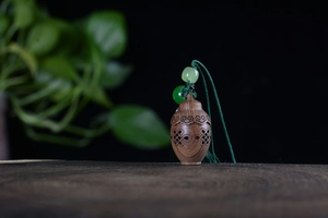 Detailed view of hand-carved green sandalwood sachet pendant with elegant green beads
