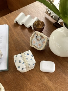 Detail of floral fabric earphone pouches with zipper and metal ring on wooden table